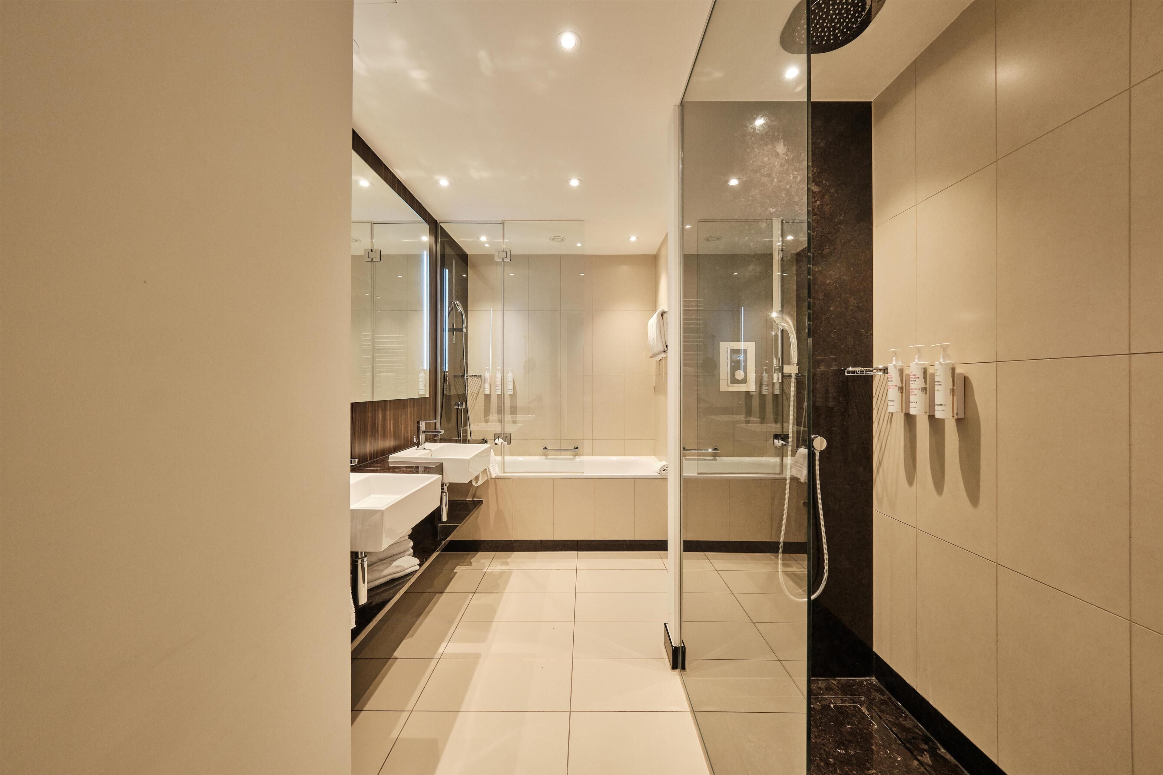 A modern bathroom with a glass shower enclosure, a bathtub, and a vanity with a sink.
