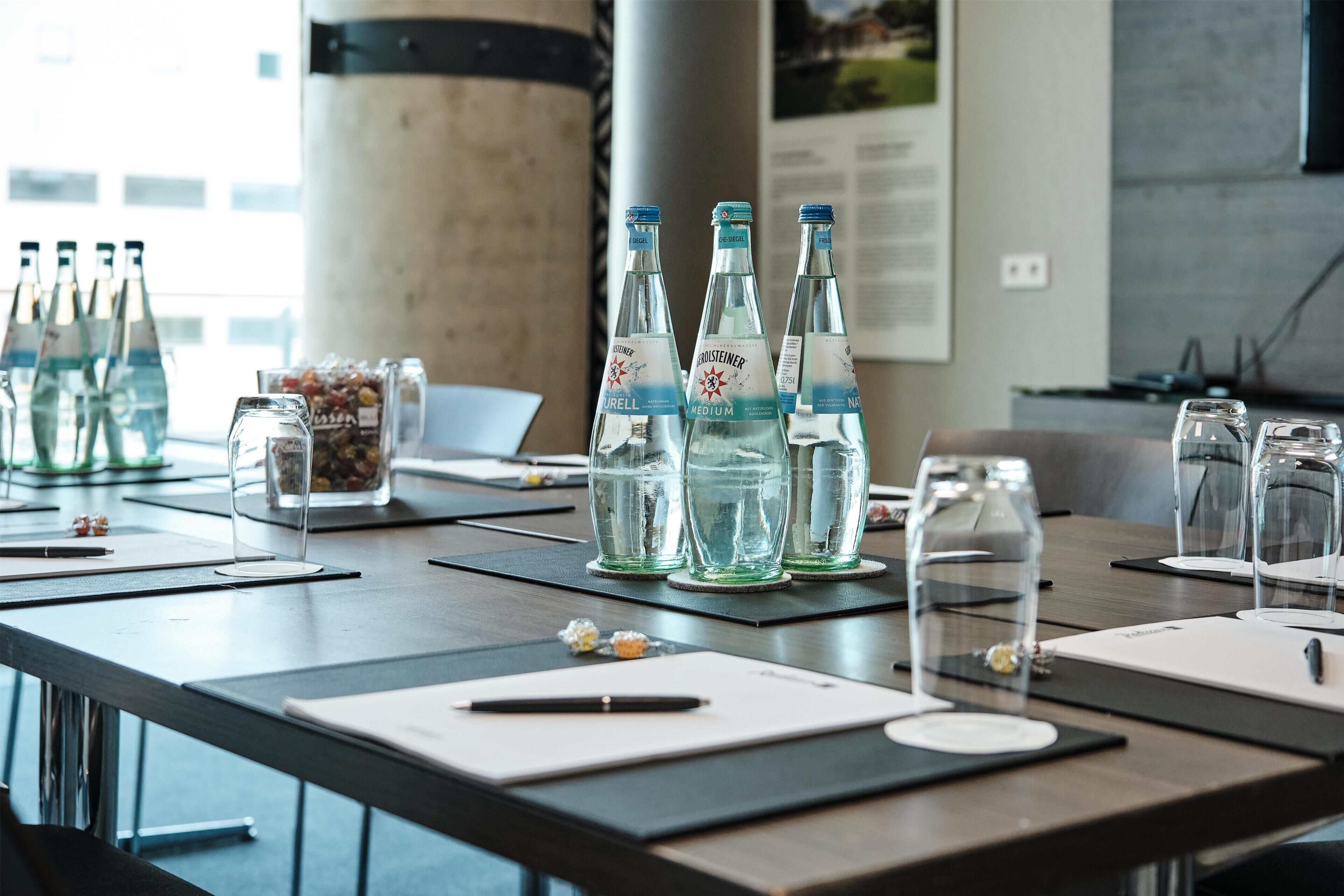 A conference table with water bottles, glassware, and documents.