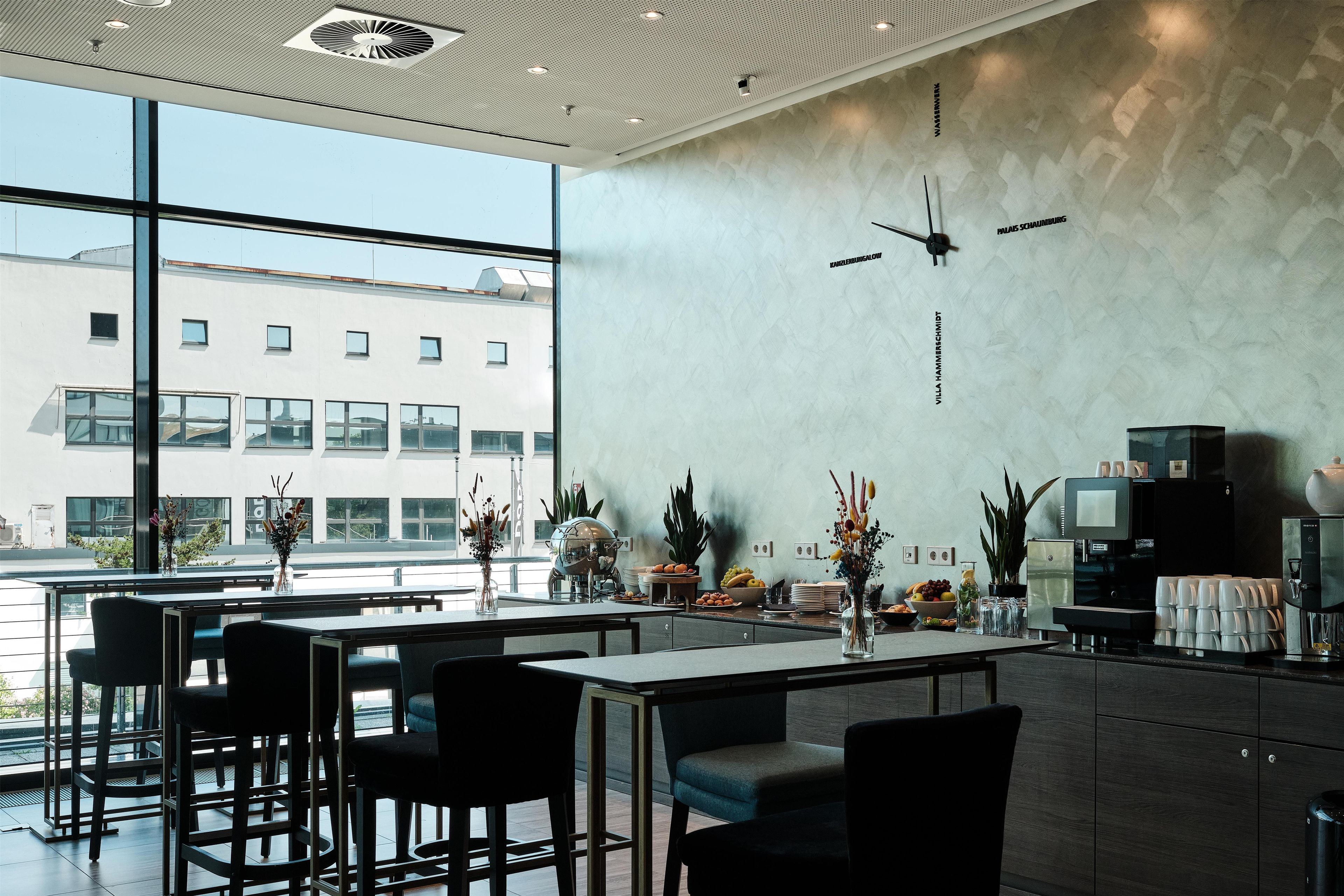 Un intérieur moderne avec un bar, des espaces pour s’asseoir et une vue sur le paysage urbain.