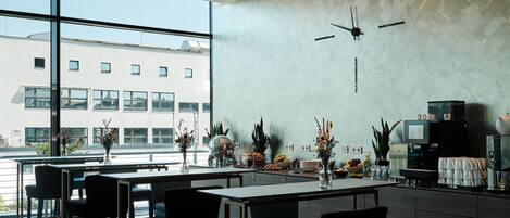 Un intérieur moderne avec un bar, des espaces pour s’asseoir et une vue sur le paysage urbain.
