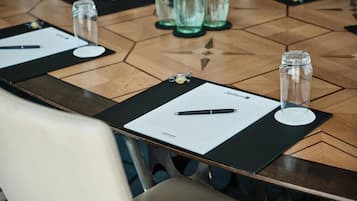 A conference table with a black placemat, a pen, a glass of water, and a bottle of water.