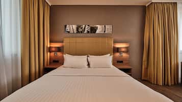 A hotel room with a large bed, two bedside tables with lamps, a headboard, and a wall-mounted artwork.