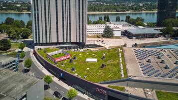 A modern building with a flat roof, a parking area, and a green space with solar panels.