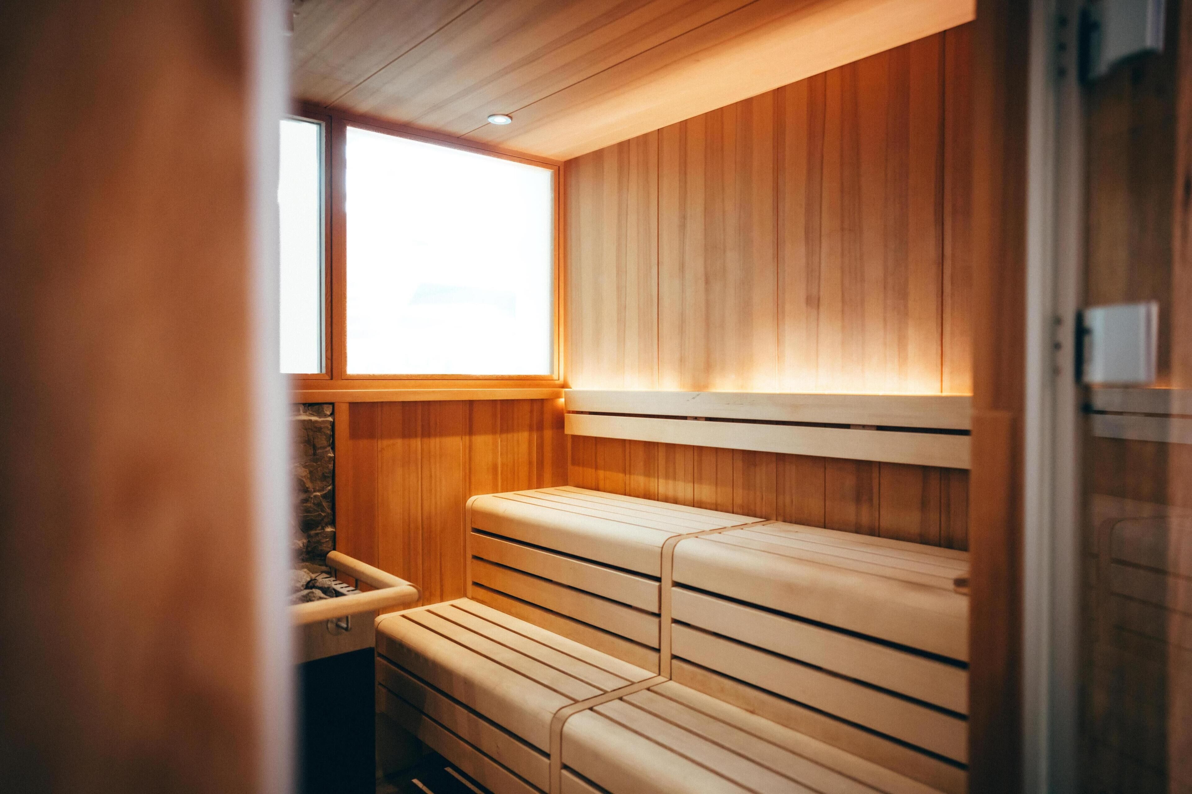 A sauna with wooden benches and a stone wall.