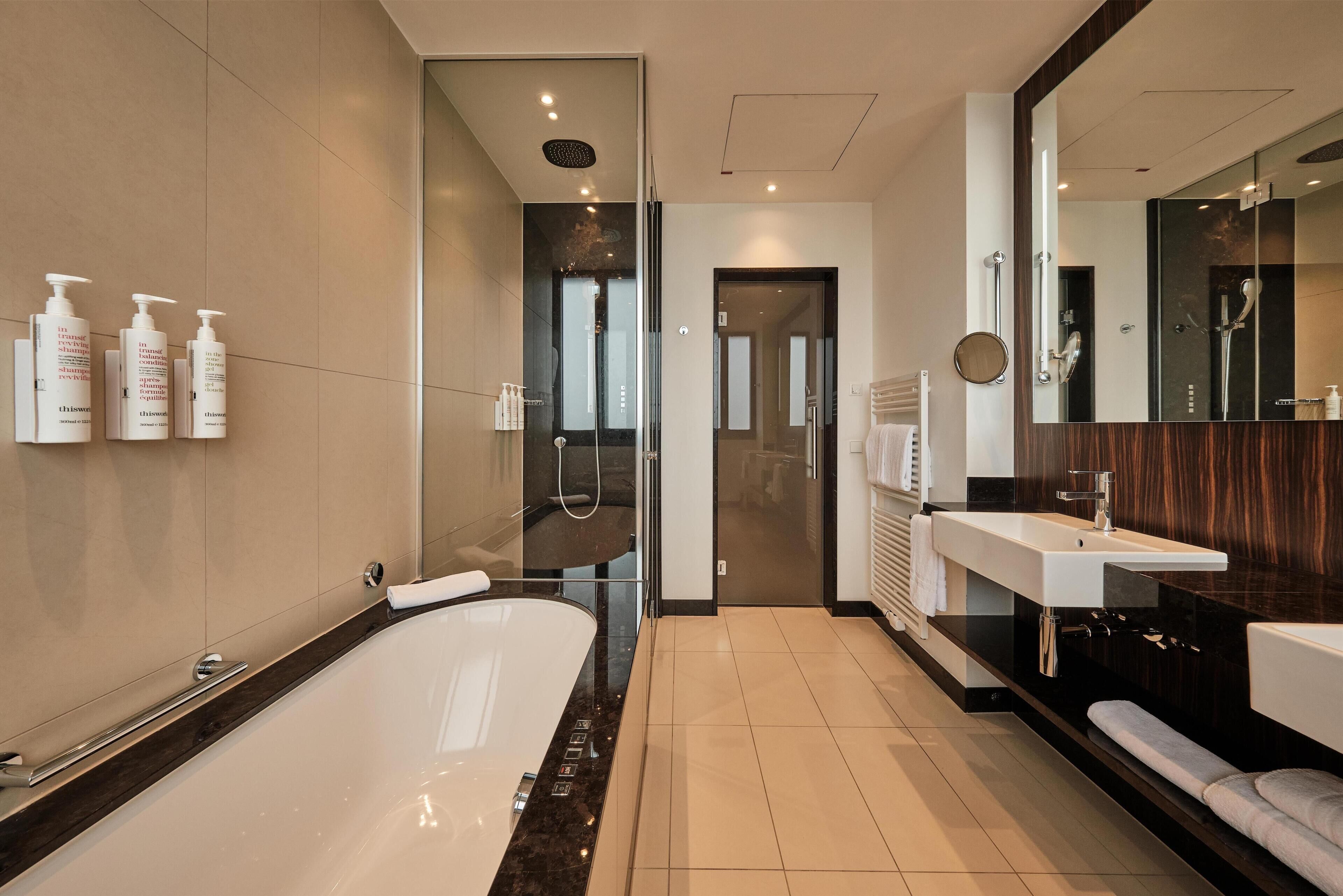 A modern bathroom with a large bathtub, a shower area, and a vanity with a mirror.
