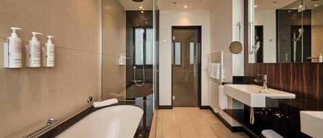 A modern bathroom with a large bathtub, a shower area, and a vanity with a mirror.