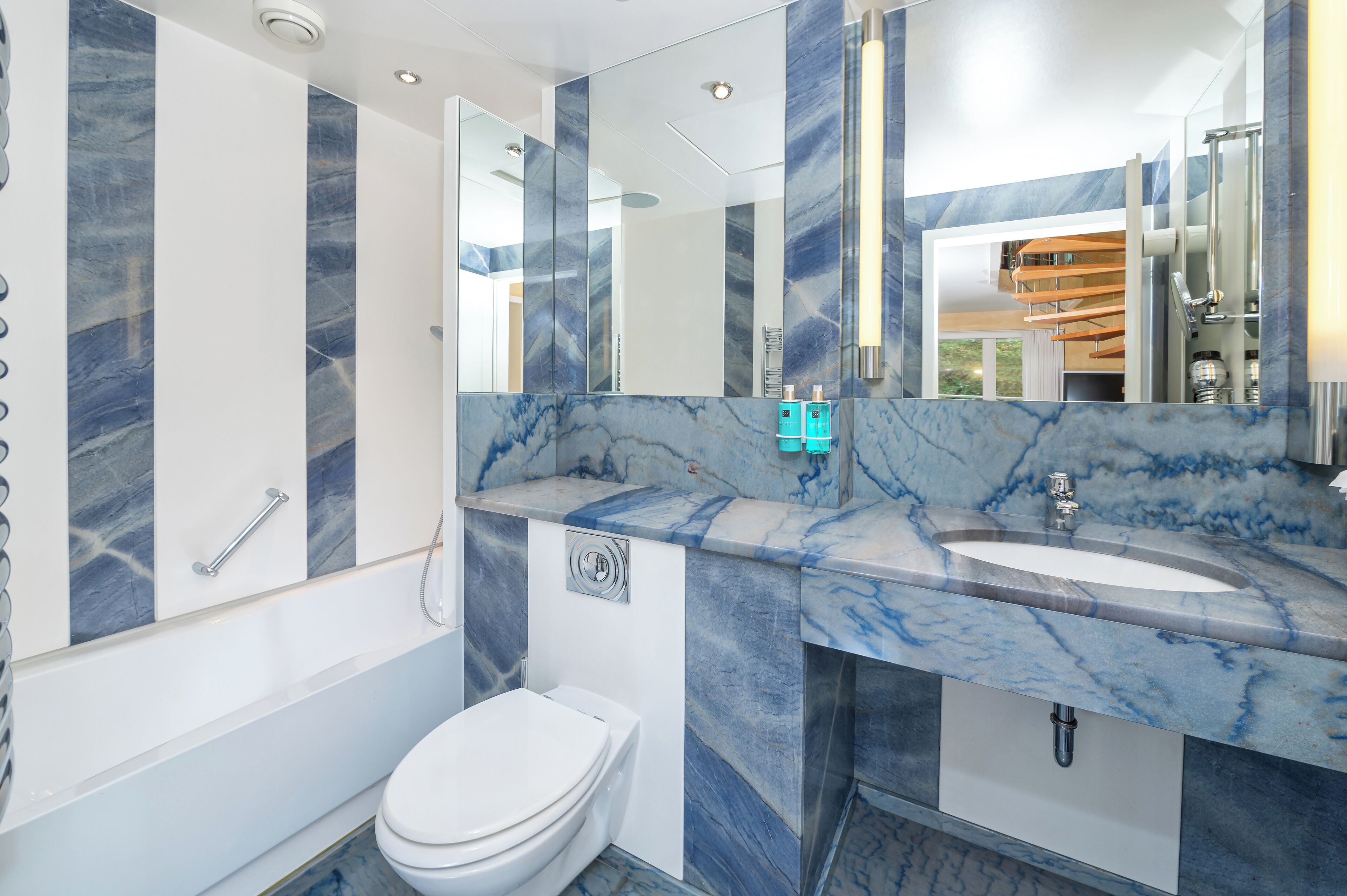 Un bagno moderno con un mobile lavabo in marmo, una vasca e un water.