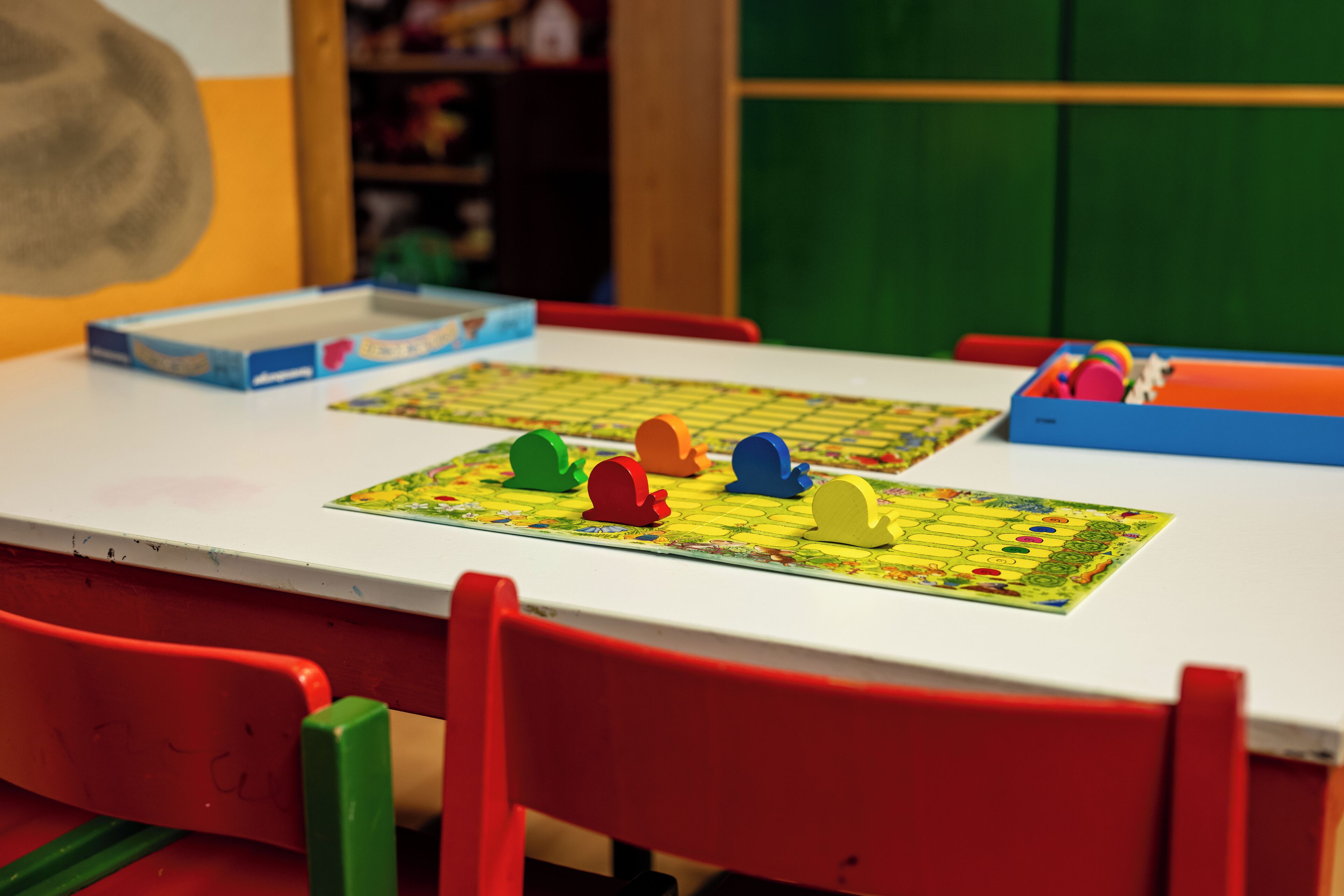 Una mesa con un juego de mesa y una caja, rodeada de sillas rojas.