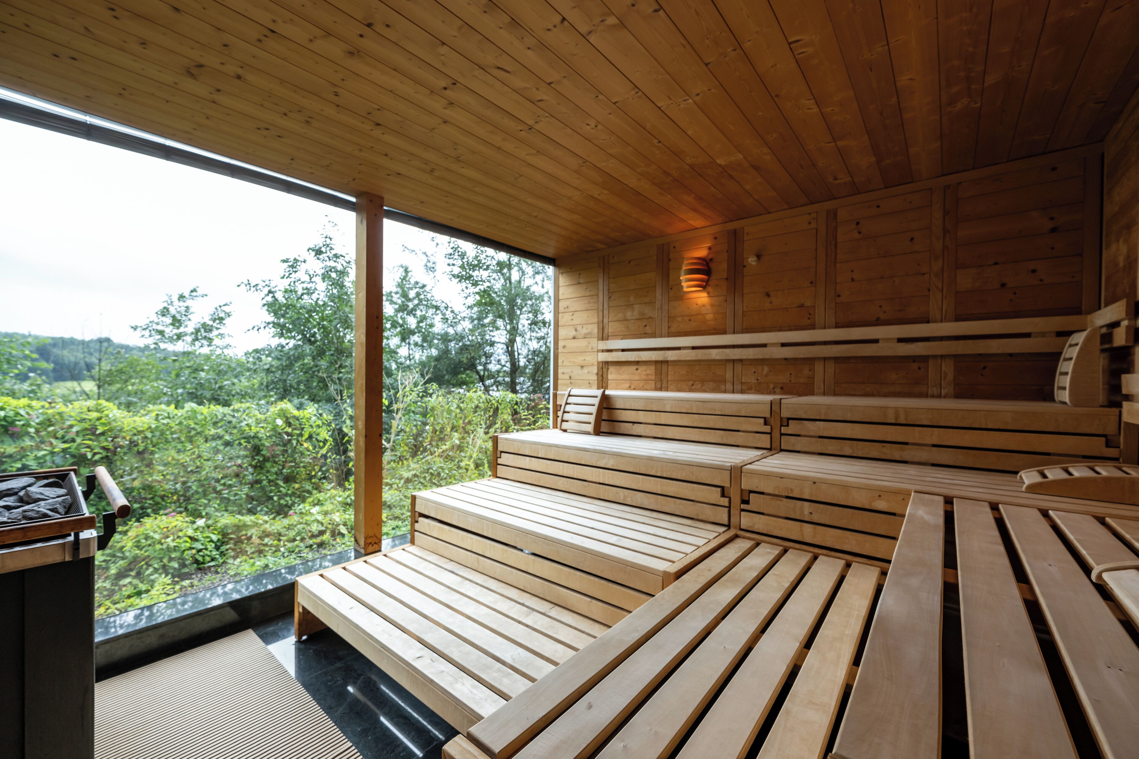 A wooden interior with a large window, wooden benches, and a small table.