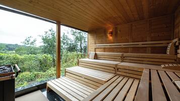 A wooden interior with a large window, wooden benches, and a small table.