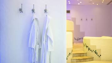 A bathroom with white towels hanging on hooks and a tiled floor with a geometric pattern.