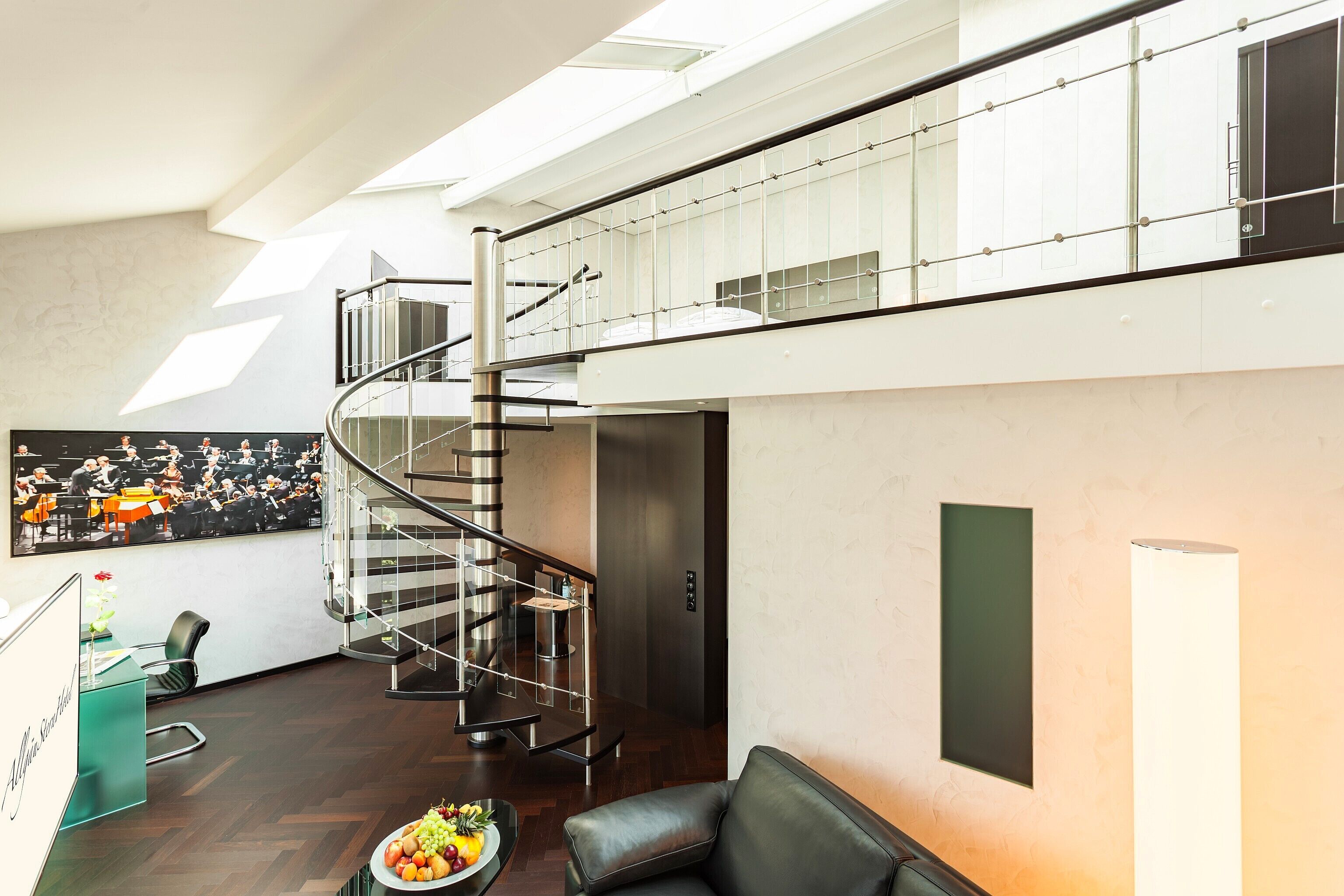Un intérieur moderne agrémenté d’un escalier en colimaçon, d’un comptoir d’accueil et d’un coin repas avec un panier de fruits.