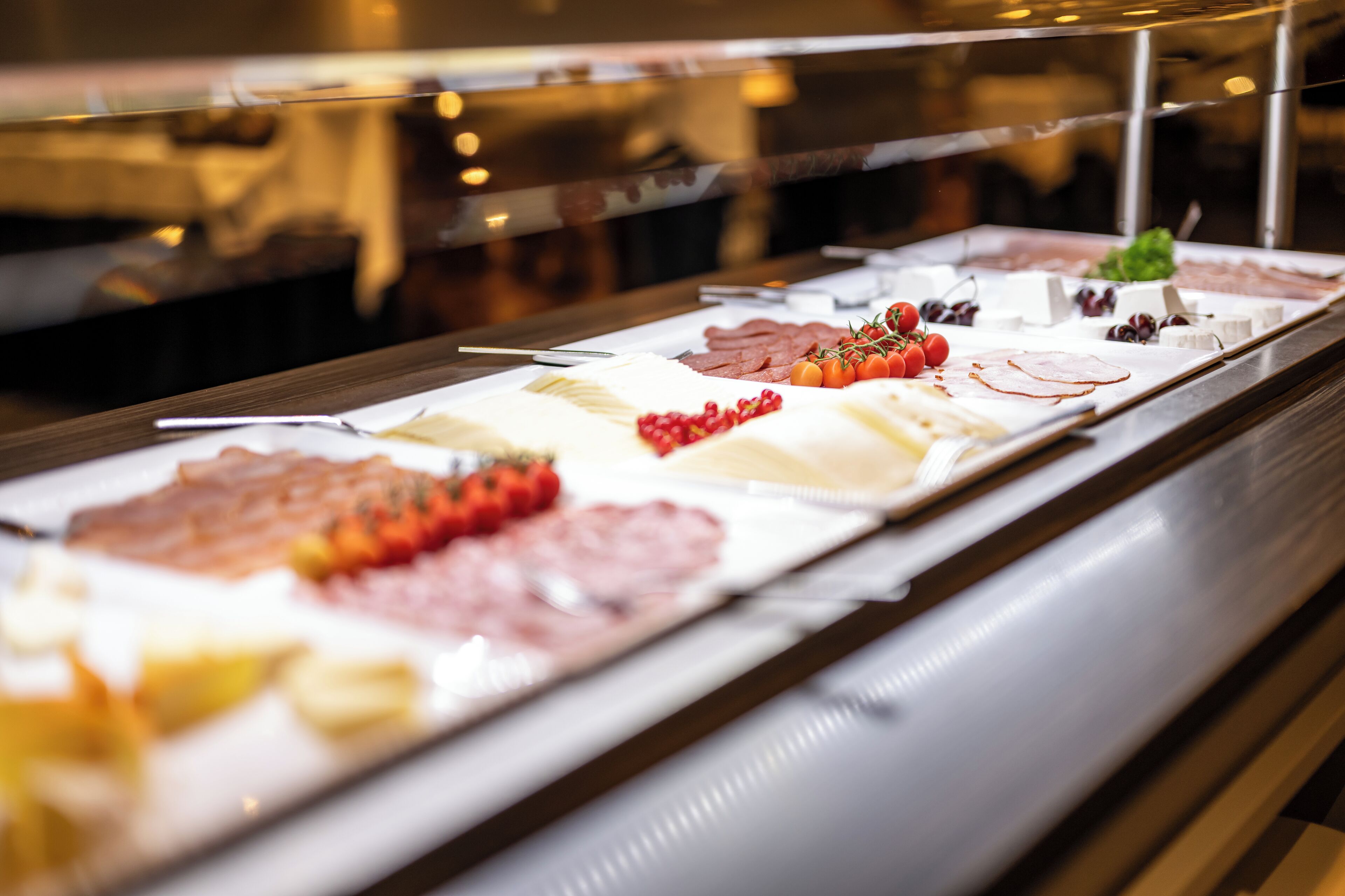 Ein Buffet mit verschiedenen Speisen, darunter Fleisch, Käse und Obst.