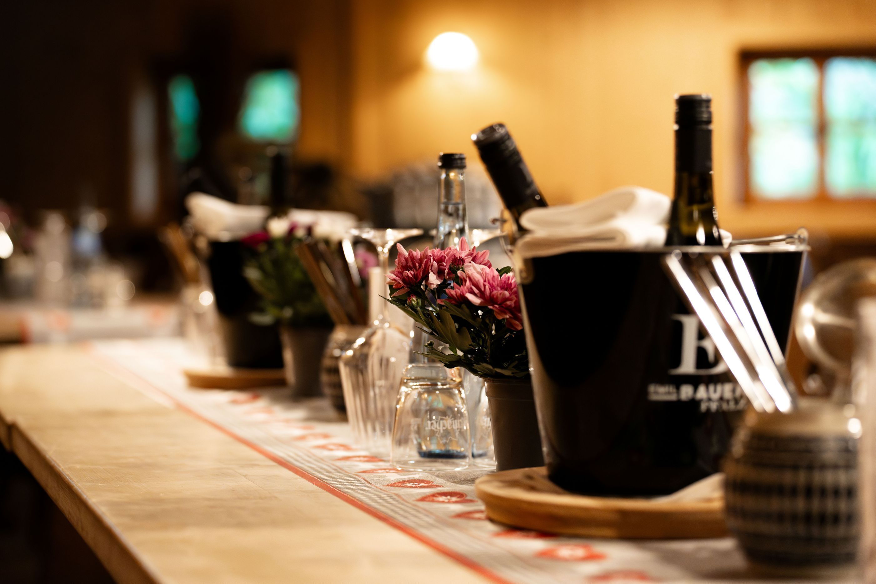 A bar area with bottles, glasses, and a wooden counter.