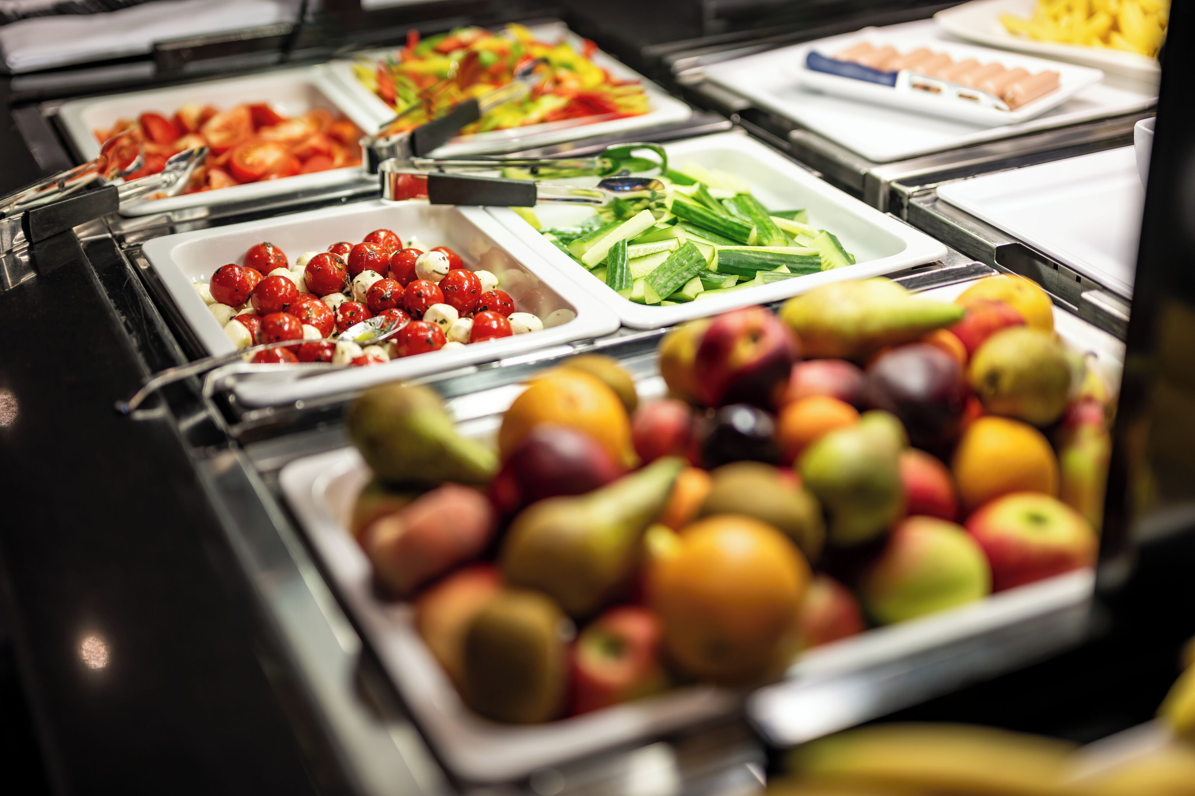 A buffet with various food options including fruits, vegetables, and salads.