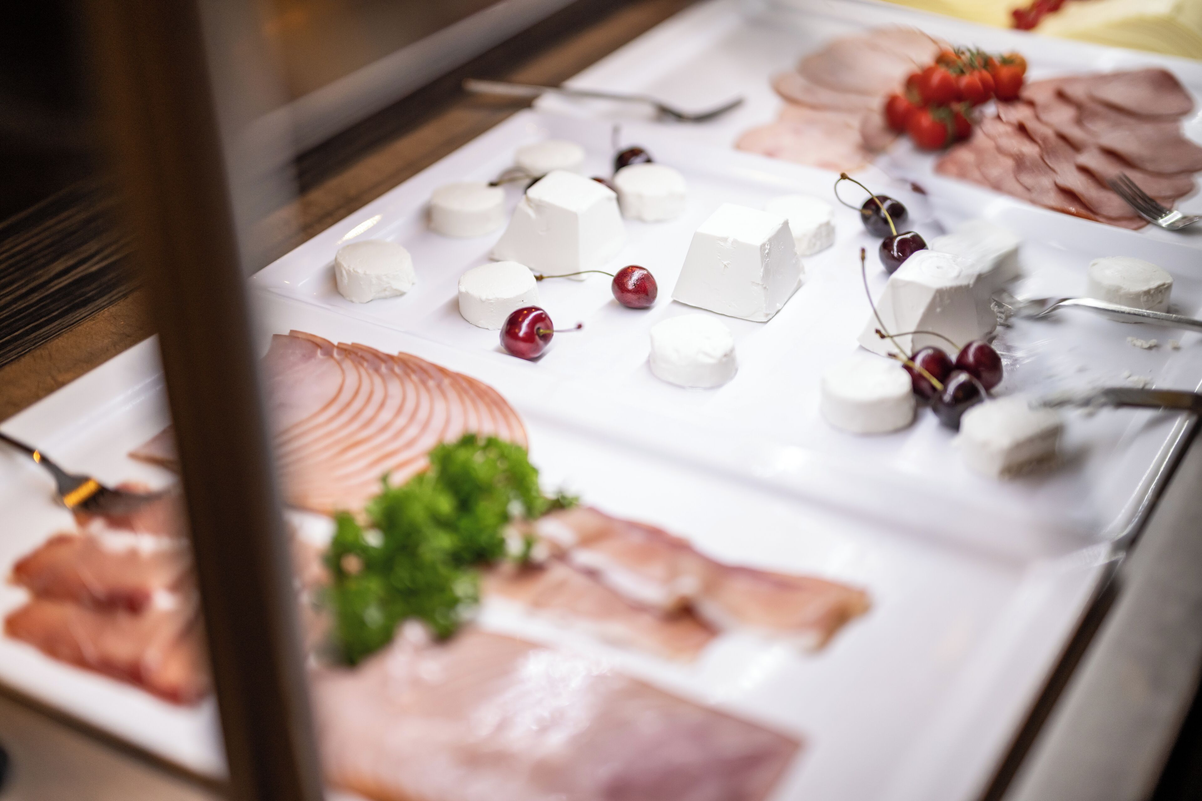 A buffet with various cheeses, meats, and fruits.