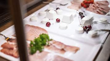 Un bufé con diversos quesos, carnes y frutas.
