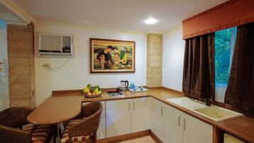 A kitchen with a dining area, a painting on the wall, and a window with curtains.
