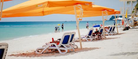 Am Strand, weißer Sandstrand, Sonnenschirme, Strandtücher