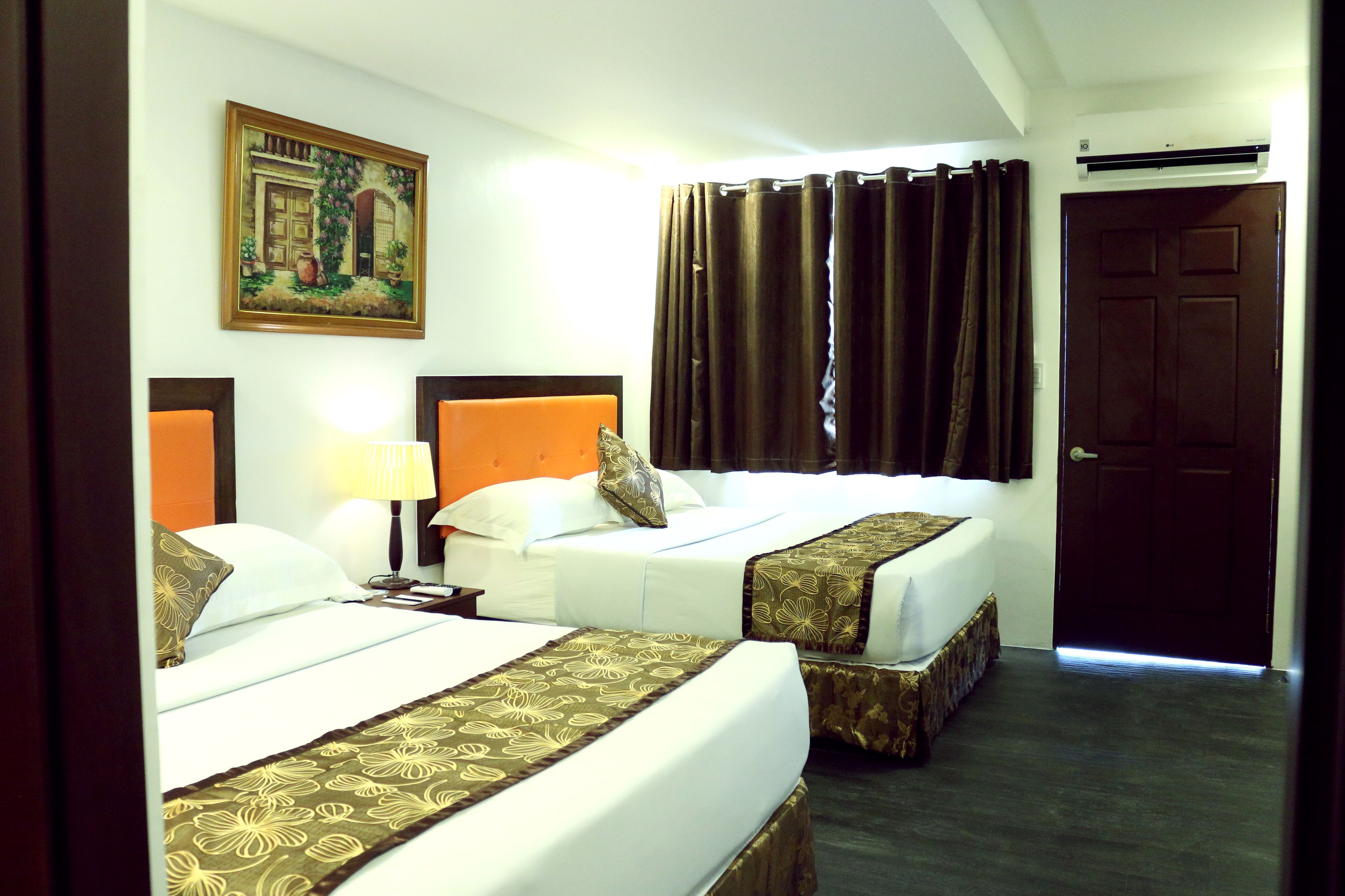 A hotel room with two beds, a painting on the wall, a door, and a curtain.