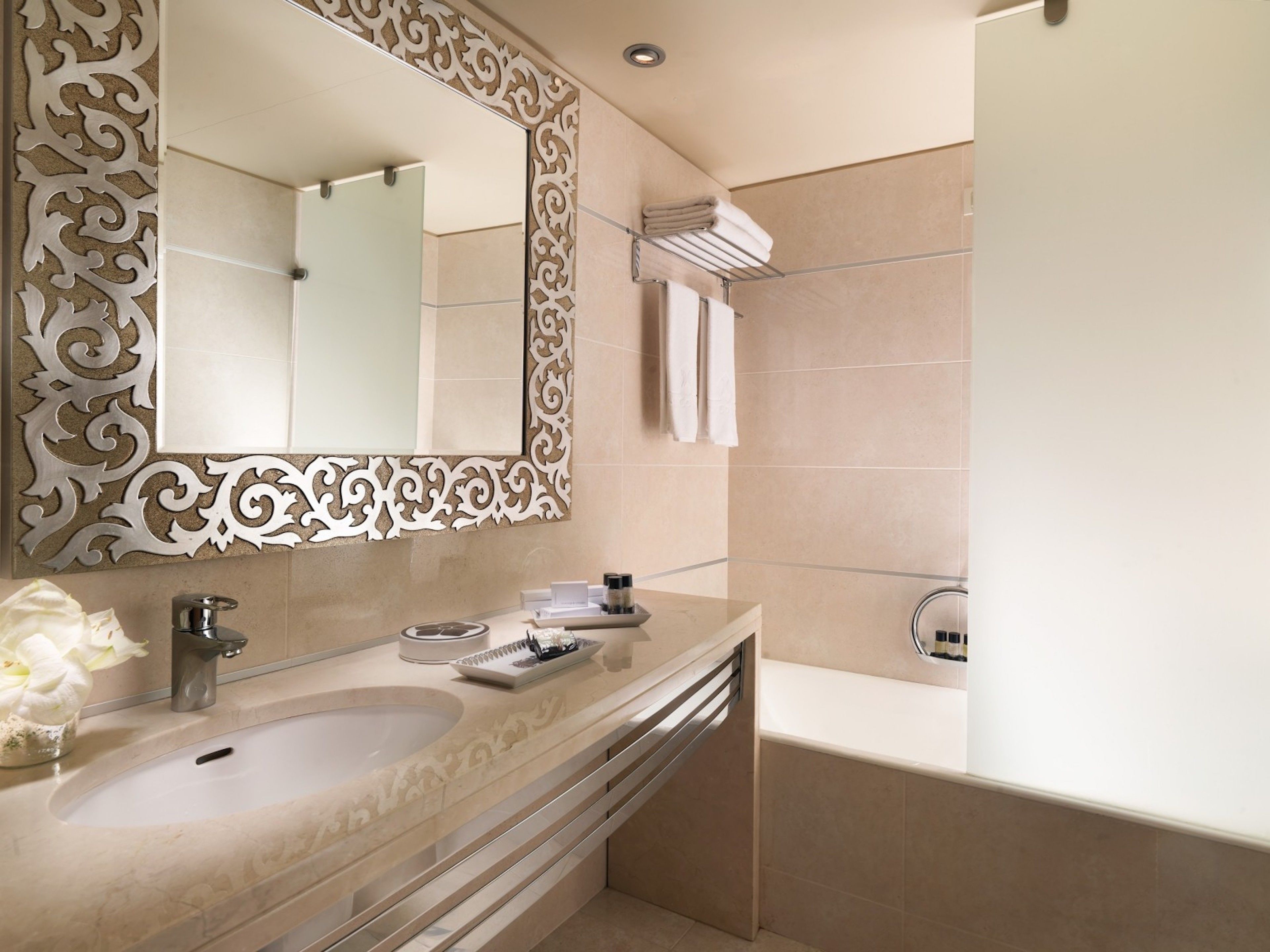 A modern bathroom with a large mirror, a sink, and a bathtub.