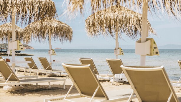 Beach chairs and thatched umbrellas on a sandy beach with a view of the sea. - Divani Escape- Adults only (Vari-Voula-Vouliagmeni)