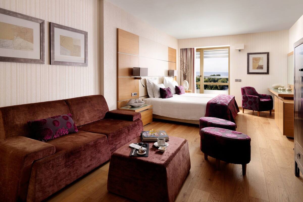 Ein modernes Hotelzimmer mit einem großen Bett, einer Couch, einem Couchtisch und einem Essbereich.