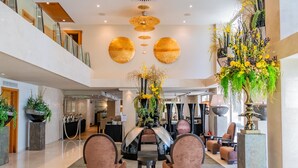 A spacious lobby with a high ceiling, modern furniture, and decorative plants. - Divani Escape- Adults only (Vari-Voula-Vouliagmeni)