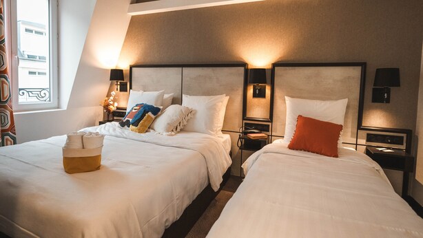 Habitación de hotel con dos camas, ventana con vistas y lámparas de noche.