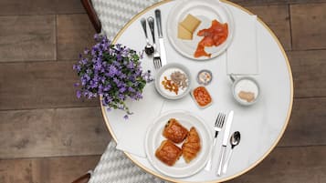 Una mesa redonda de comedor con platos de comida, cubiertos y un pequeño jarrón de flores.