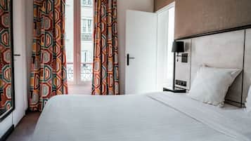 Quarto de hotel com cama, mesa de cabeceira, luminária e vista para o exterior.