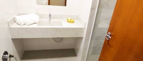 Un baño moderno con lavamanos de mármol, espejo y zona de ducha.