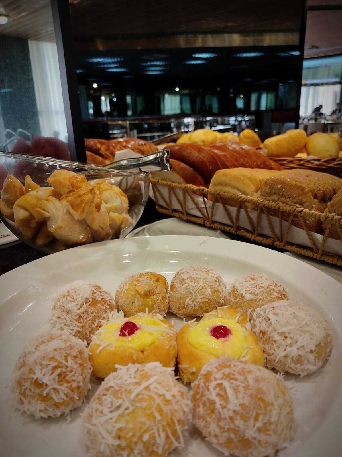 A buffet with various food items including bread, pastries, and coconut-covered sweets.