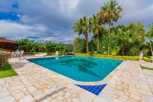 A swimming pool with stone tiles and palm trees.