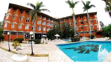 Un hotel con piscina, zona de estar exterior y palmeras.