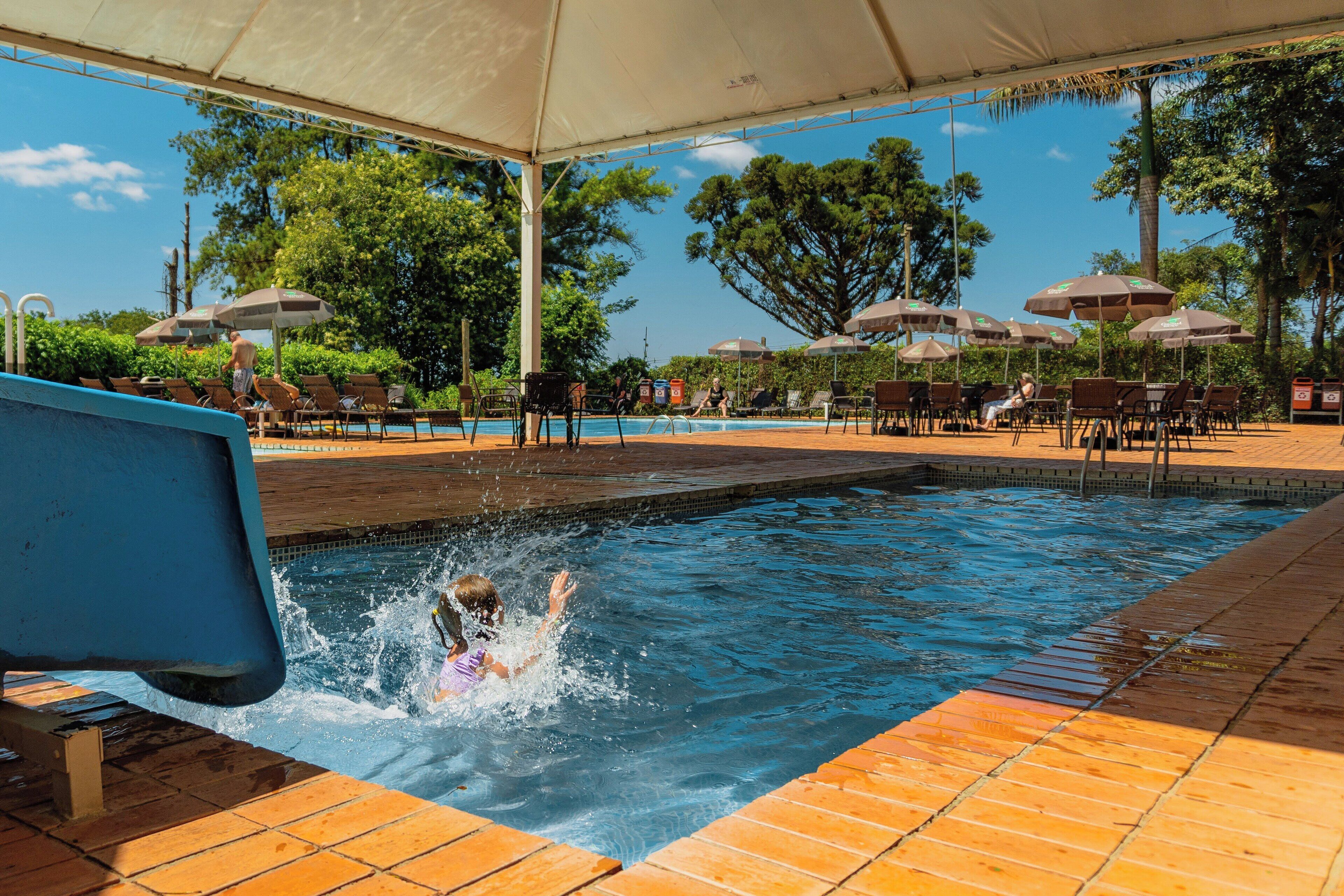 A swimming pool area with a covered section, lounge chairs, and umbrellas.