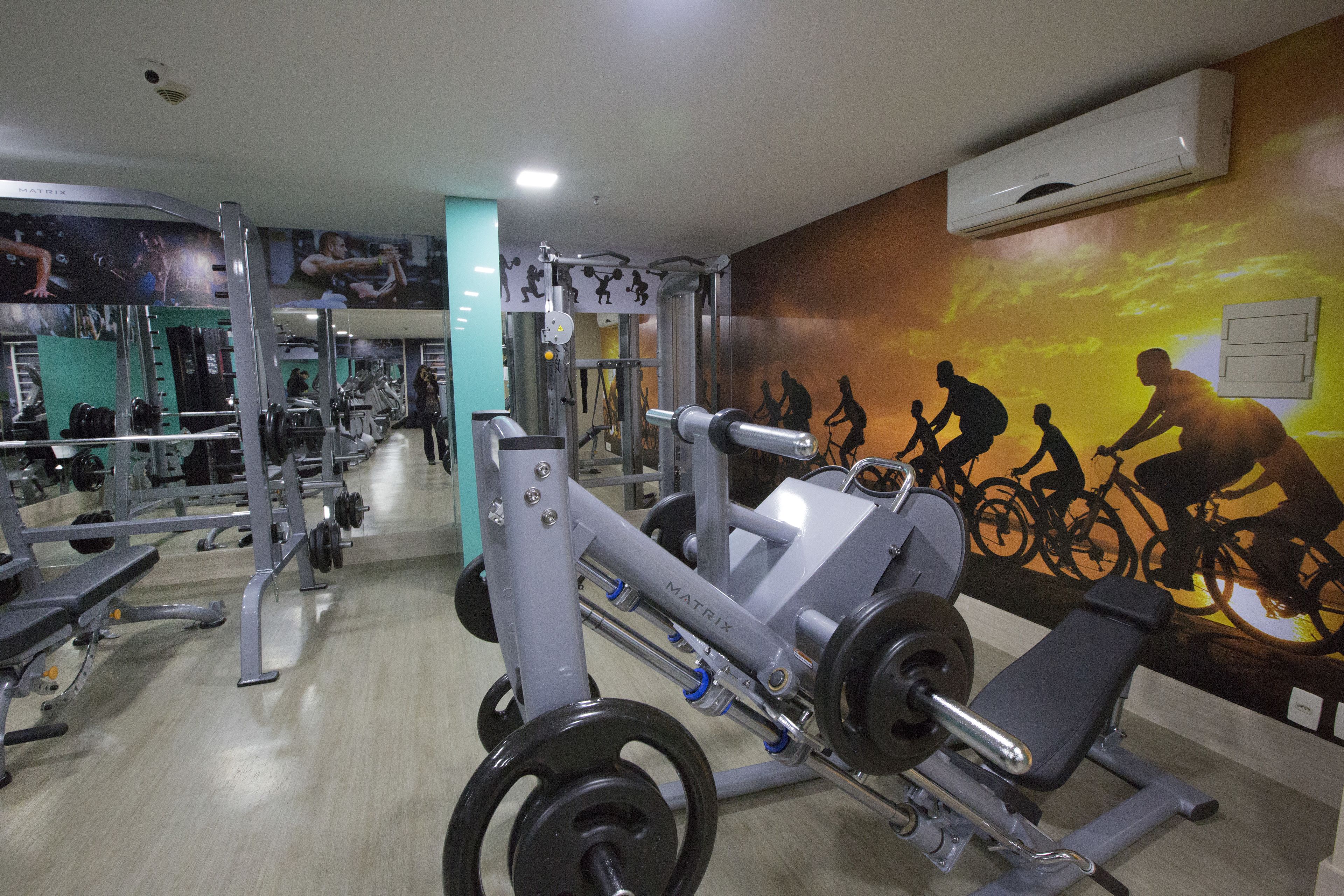 A gym with various exercise equipment, including a bench press and weight racks.
