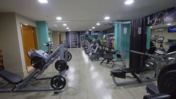 A gym with various exercise machines, a weight bench, and a wall-mounted TV.