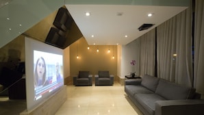 A modern living room with a large flat-screen TV, two armchairs, a sofa, and a coffee table. - Nobile Suites Monumental (Brasília)