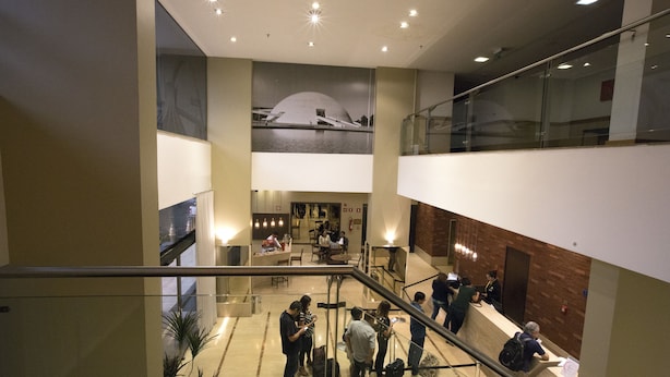 A spacious lobby with a central seating area, a staircase, and a reception desk. - Nobile Suites Monumental (Brasília)