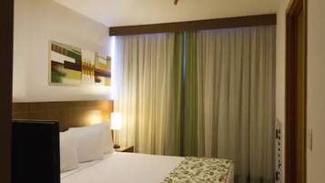 Una habitación de hotel con cama, mesita de noche, lámpara y un cuadro en la pared.