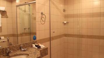 Un baño con lavamanos, espejo y cabina de ducha de vidrio.