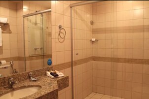 Un baño con lavamanos, espejo y cabina de ducha de vidrio.