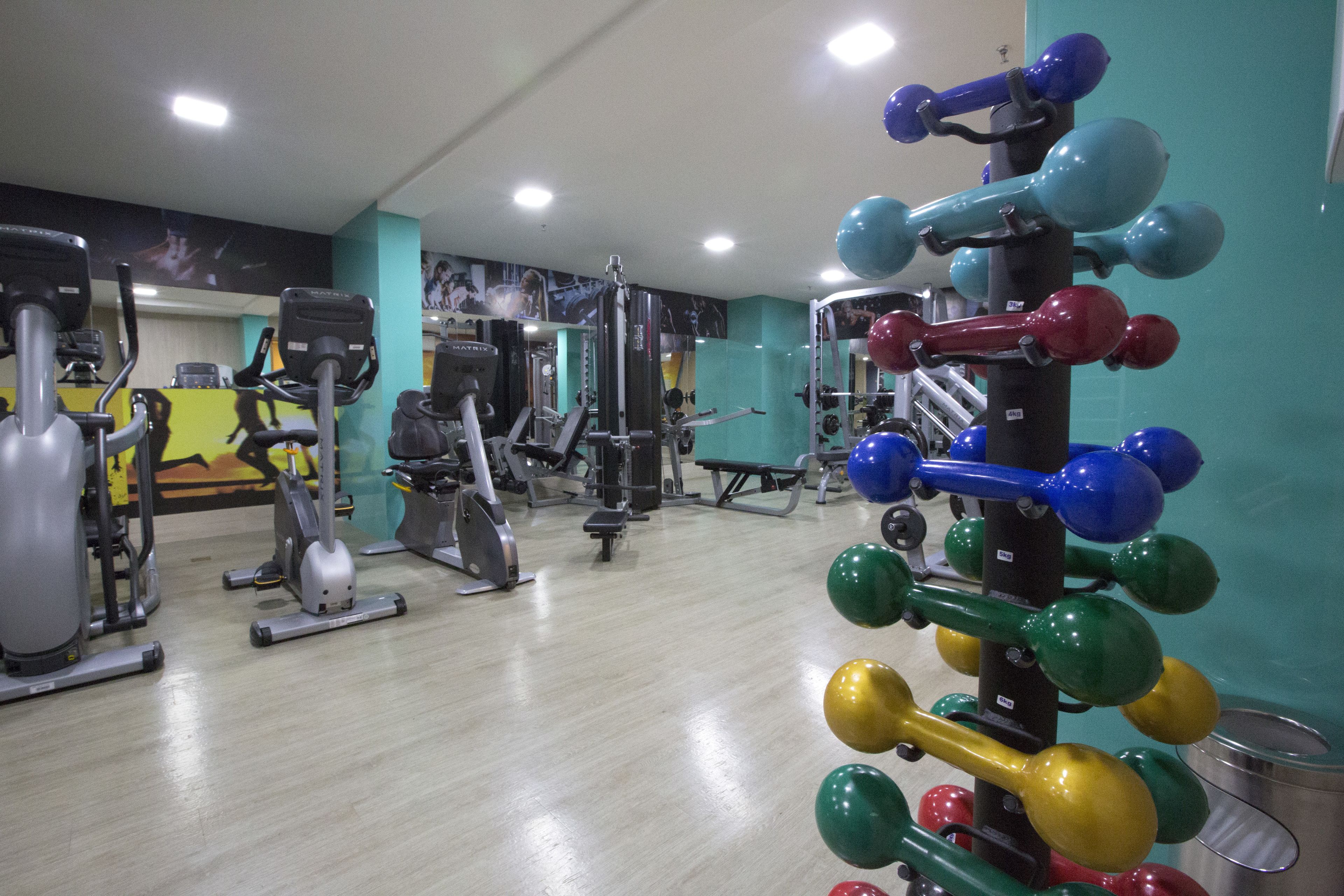 Uma academia com diversos equipamentos de exercício, incluindo esteiras, bicicletas ergométricas e pesos livres.