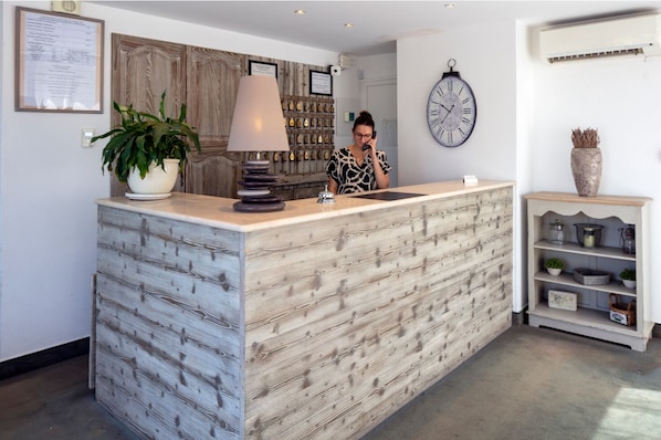 A reception desk with a wooden finish, a clock, and a potted plant.
