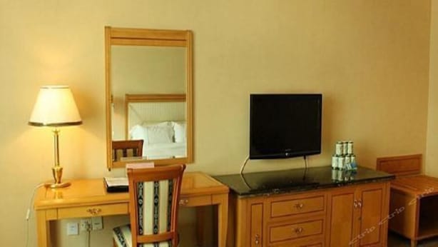 A hotel room with a wooden desk, a lamp, a television, and a mirror. - New Pearl River (Guangzhou)