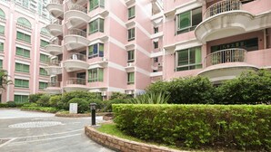 A multi-story pink building with balconies, a landscaped garden area, and a paved entrance. - New Pearl River (Guangzhou)