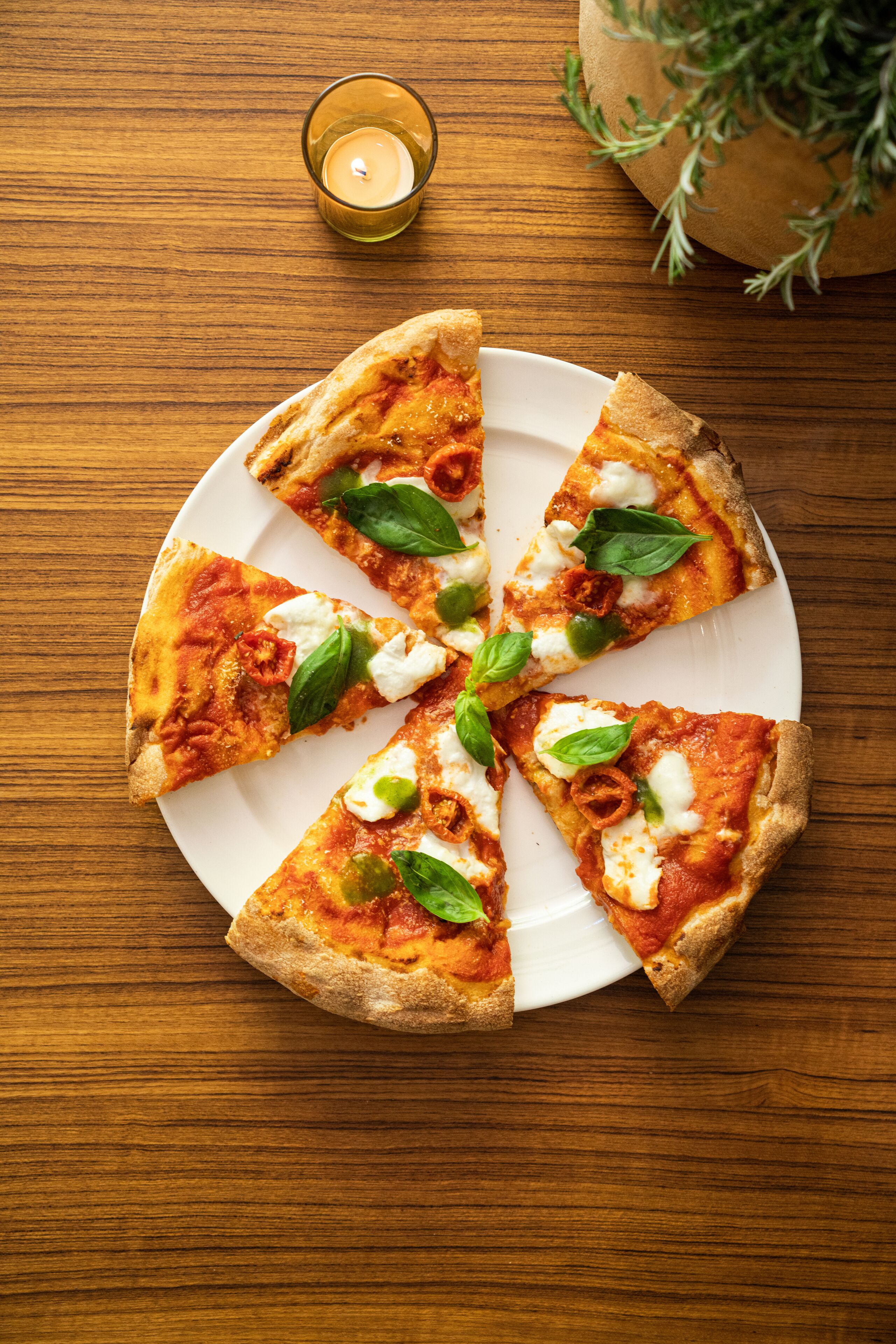 A pizza on a white plate with slices missing, placed on a wooden table.