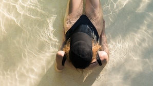 Una persona recostada en la playa, con agua cristalina a su alrededor.