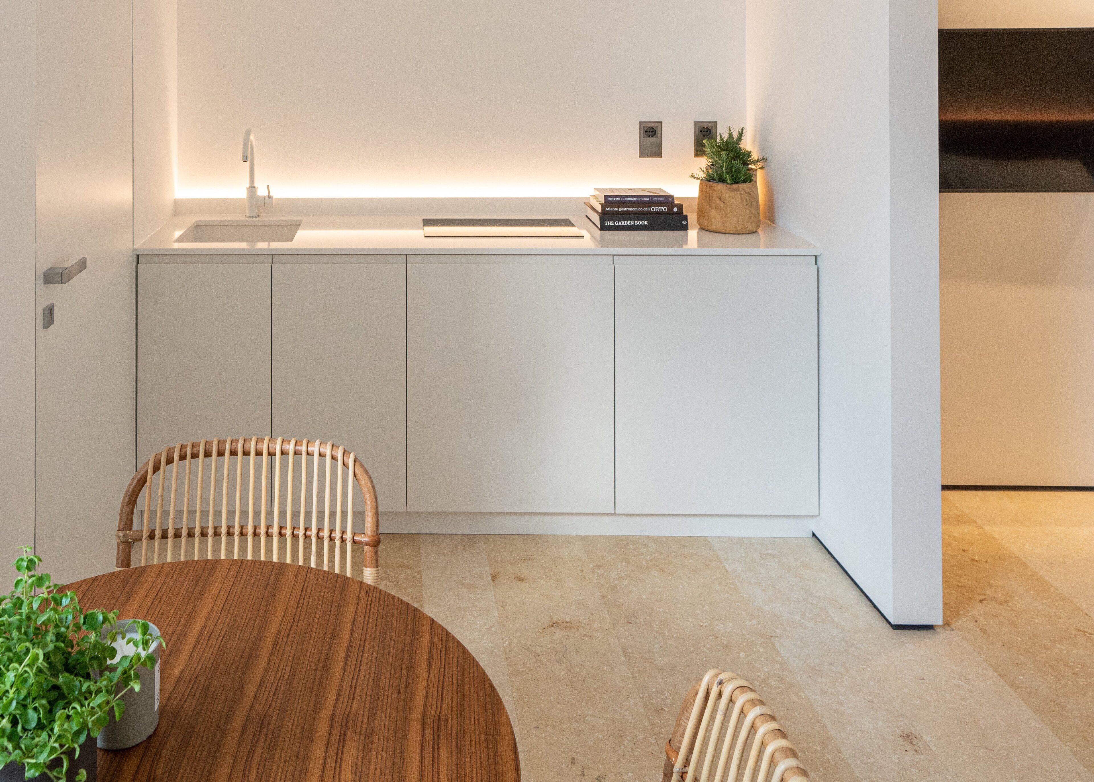 A modern kitchen with white cabinets, a wooden dining table, and chairs.